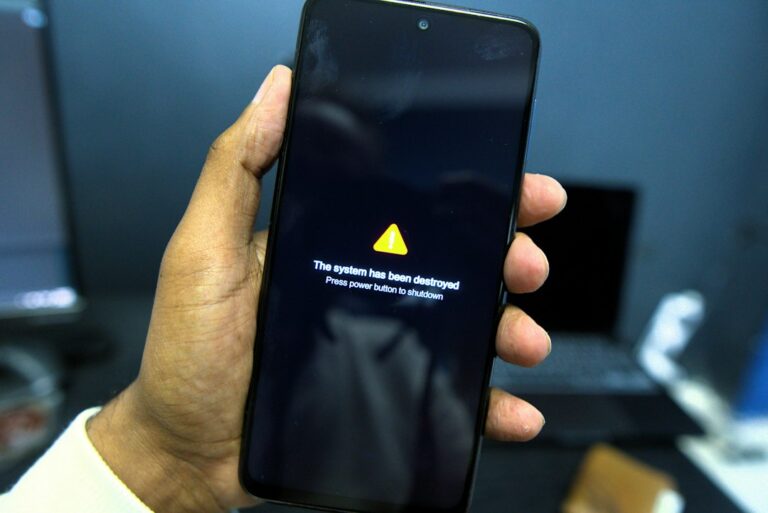 A smartphone held in one hand showing a full-screen warning message